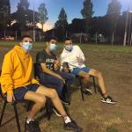 tres jovenes con tapaboca sentados en una silla en la cacha del complejo