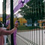 mujeres colgando cintas violetas en una reja y otra sacando fotos al otro lado