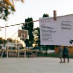 poemas colgando de una cuerda y adolescentes de al fondo jugando al basquetbol