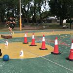 Se ve un circuito de gimnasia delimitando por conos y objetos deportivos
