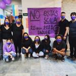 Personas posan frente a cartel 