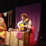 Un músico y una actriz vestida de señora mayor solos en el escenario en la obra Las aventuras de Serafín 