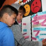 Niños participan de un juego con palabras en un tablero de papel
