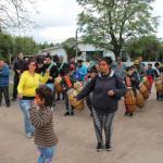 Personas con tambores y otras bailando recorren una calle del barrio