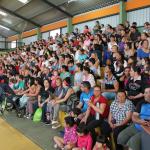 Gran cantidad de público mira la muestra desde las gradas del gimnasio