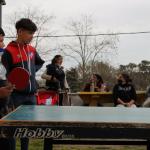 niño jugando al ping pong en frente a la mesa del juego
