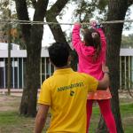 adolescente sosteniendo una niña que camina sobre una cuerda