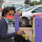 mujer pintando pinos de estacionamiento pintados de colores