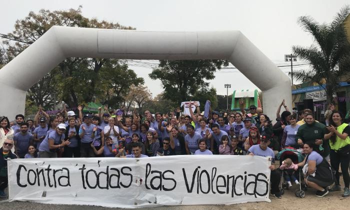Corredoras y corredoras con cartel que dice contra todas las violencias en el arco de partida