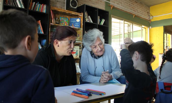 Personas mayores intercambian con niñas y niños en el hall del complejo