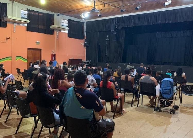 Publico de espaldas frente a un escenario con una función a punto de comenzar 