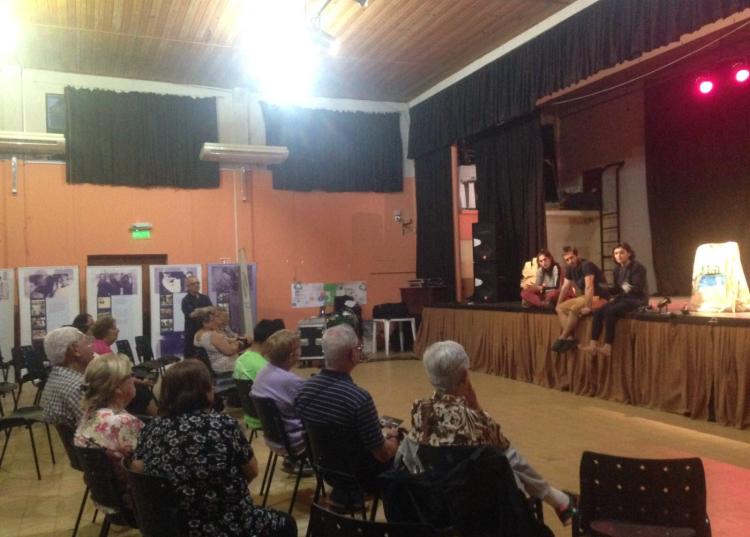 Una actriz y un actor están sentados en el escenario conversando con el público