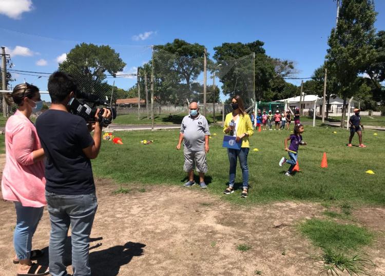 Una periodista habla con un referente de SACUDE frente a una cámara en la cancha del complejo