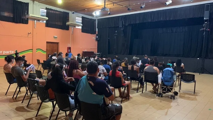 Publico de espaldas frente a un escenario con una función a punto de comenzar
