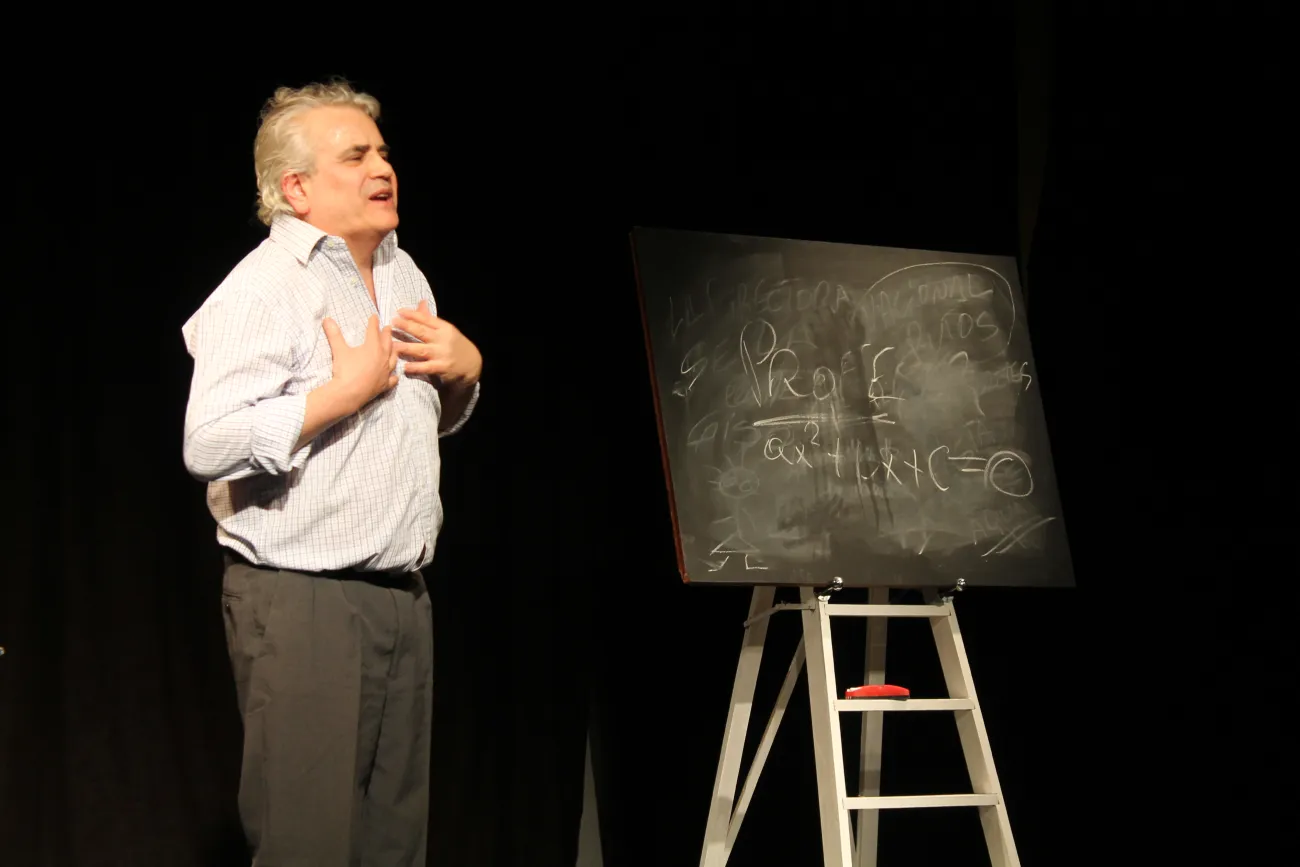 Un actor interpreta a un profesor, se lo ve junto a una pizarra